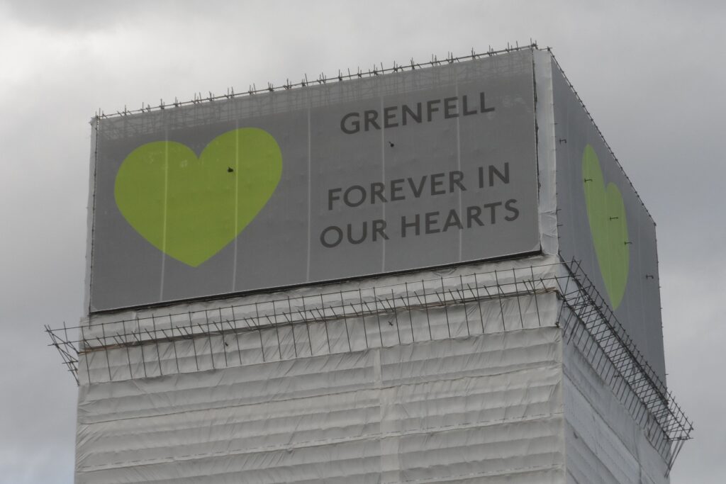 Image shows the top of Grenfell Tower with a message saying: "Forever in our hearts"