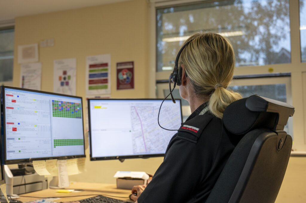 Member of staff wearing black uniform, looking at computer wearing a headset