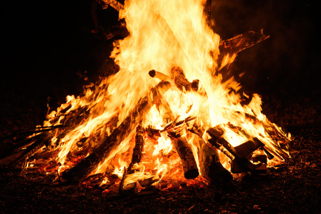 Bonfire burning at night, bright orange flames of fire, selective focus