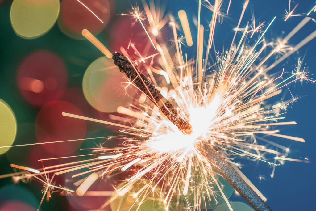 Close up image of sparkler with dark background and colourful orbs surrounding