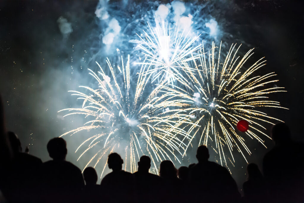 A crowd watching large yellow fireworks