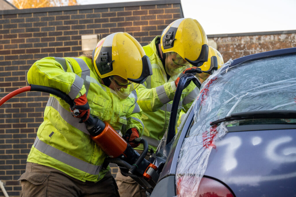 Two firefighters cutting in to a car