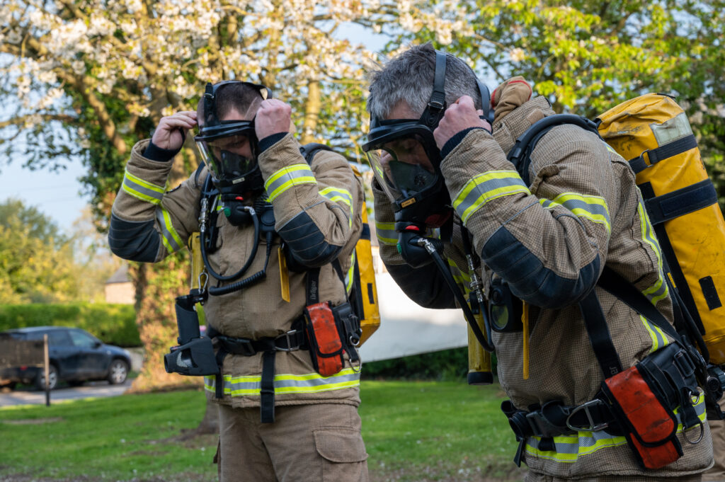 Two firefighters putting on BA kit